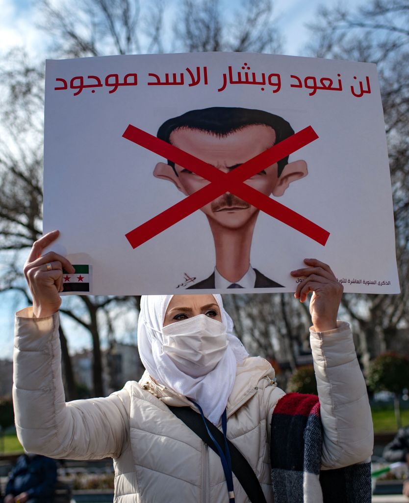 A Syrian woman holds up a banner that reads, 'We will not return as long as (Syrian President) Assad is present', during a rally marking the 10th anniversary of the start of the war in Syria, in Istanbul on March 13, 2021. - More than 3.6 million Syrians refugees live in Turkey as a result of the decade-long conflict in their home country. The UN rights chief on March 11, 2021 urged Syria's warring parties to disclose the location of tens of thousands of missing people, as she marked 10 grim years since the start of the war. (Photo by Yasin AKGUL / AFP) (Photo by YASIN AKGUL/AFP via Getty Images)