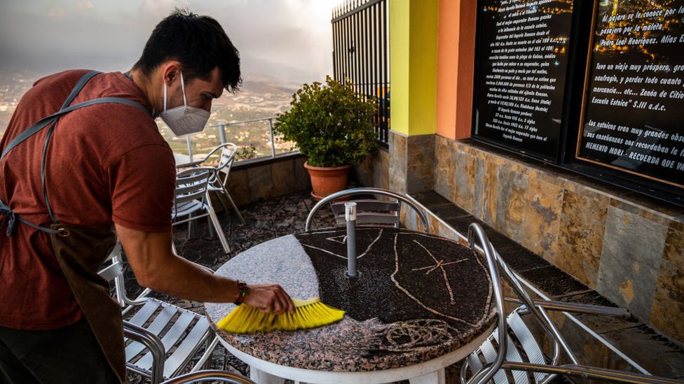Сотрудник ресторана счищает вулканический пепел