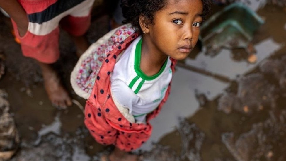 A young girl standing in muddy water