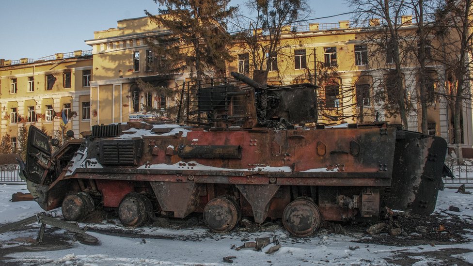 A destroyed armoured troop-carrier stands in front of a destroyed building in Kharkiv, 11 March 2022.