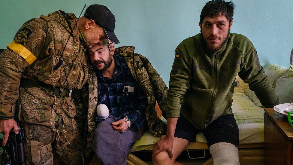 Ukrainian service personnel visit their comrades Vitaly, who lost his hand, and Pasha, who wounded his knee, as they recover in a local hospital in Brovary 10 March 2022.
