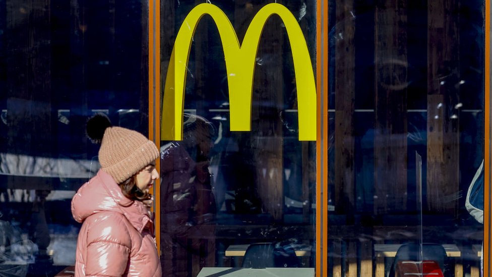 Женщина идет мимо закрытого ресторана McDonald's в Москве. Март 2022 г.