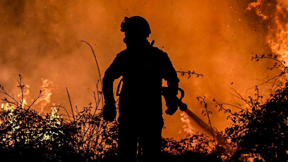 Пожарный на фоне огня в Португалии