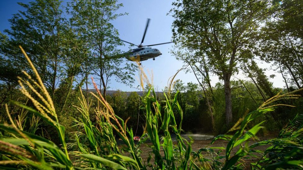 A helicopter collects water from a pond.