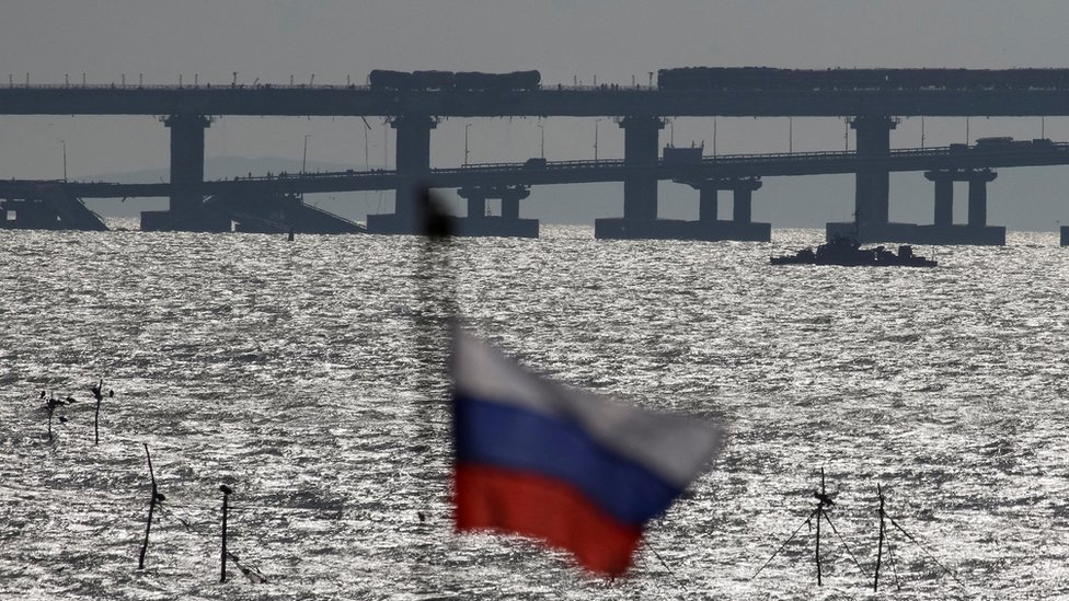Российский флаг на фоне разрушенного Крымского моста