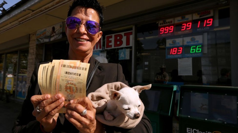 Женщина держит в руках лотерейные билеты и собаку