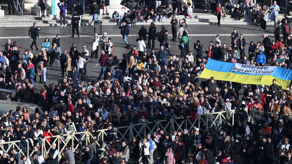 Народ на площади под балконом. Обращение на украинском флаге: "Святой отец! Молись за Украину!"