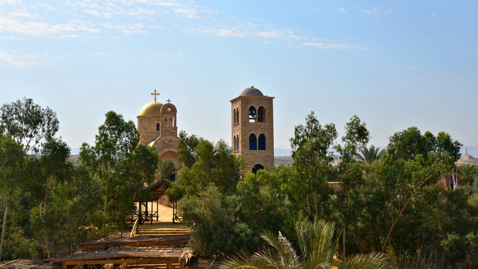 церковь с крестом и колокольня за невысокими деревьями