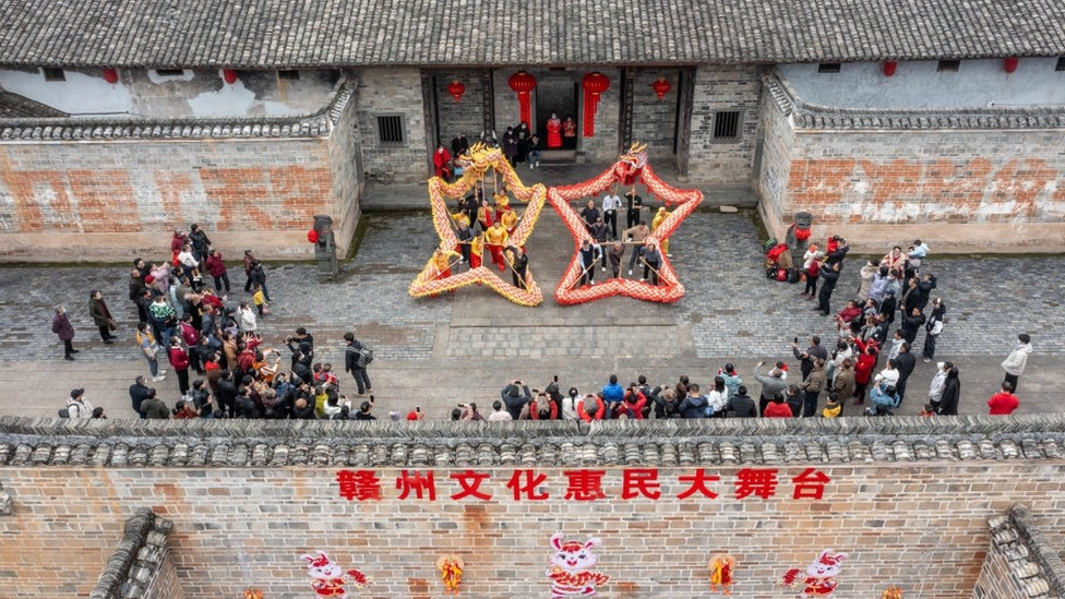 Люди наблюдают за традиционным праздничным "танцем драконов" в Хуайане, провинция Цзянсу