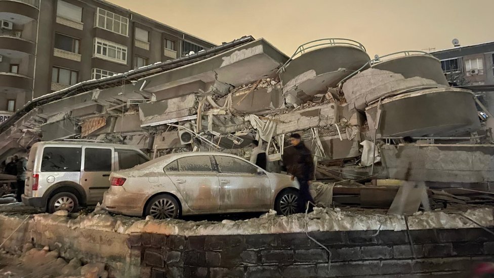 Разбитые автомобили под разрушенным зданием в Малатье, Турция.