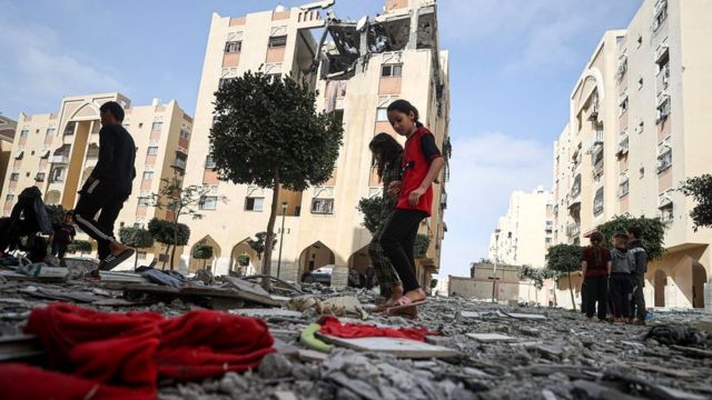 Palestinian children walk past a damaged apartment building in Khan Younis where Islamic Jihad commander Ali Hassan Ghali and two other people were killed in an Israeli strike (11 May 2023)