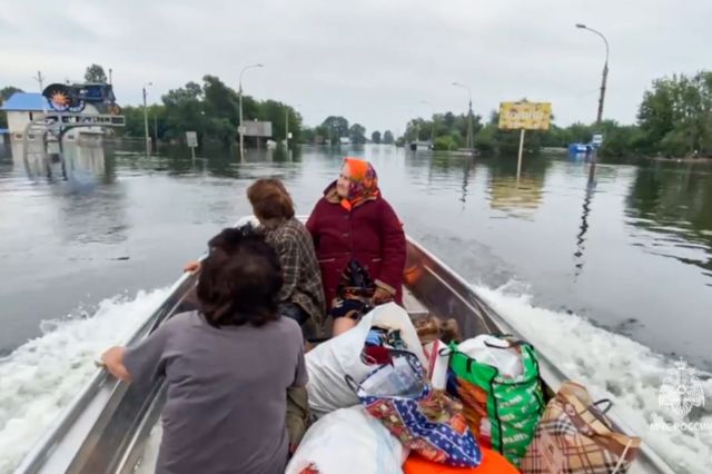женщин вывозят на лодке из места затопления