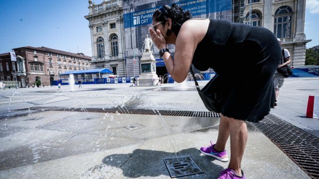 Женщина охлаждается водой из фонтана в Турине