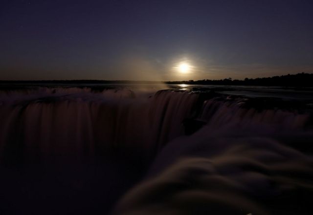 Полная луна восходит за водопадами Игуасу, на аргентинской стороне реки Игаузу.
