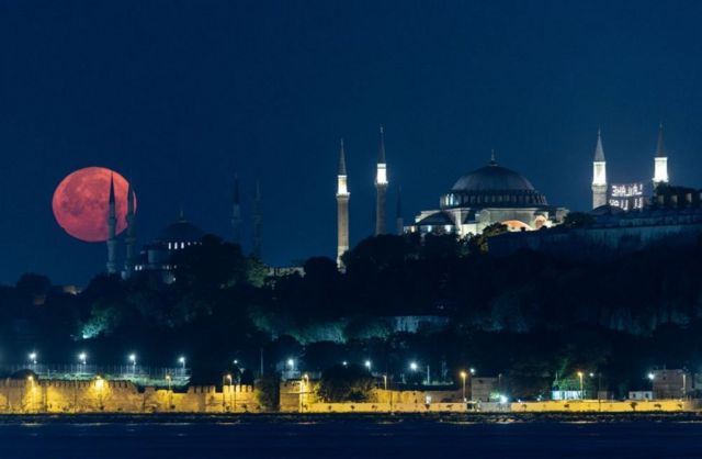 Полная луна заходит за Голубой мечетью и Большой мечетью Святой Софии в Стамбуле, Турция.