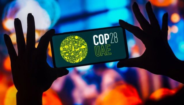 Photo of the COP28 UAE logo displayed on a smartphone screen.