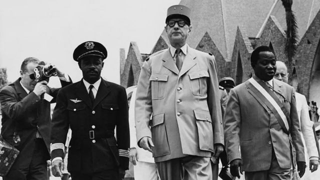 Шарль де Голль (в центре) с Бартелеми Богандой (справа), основателем Движения социальной эволюции Черной Африки (MESAN), выступающего за независимость, в 1958 году.