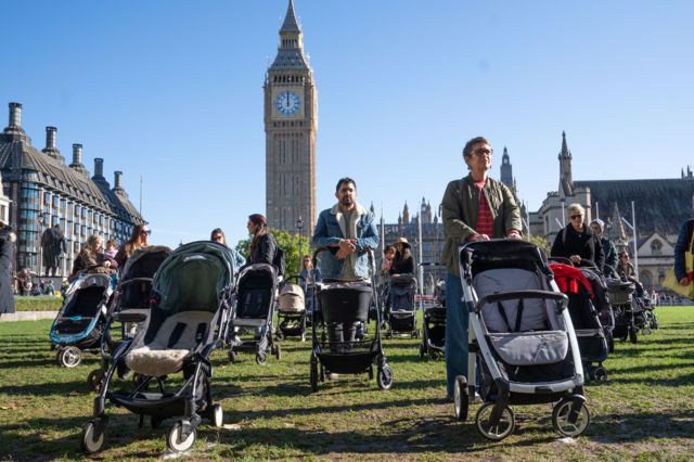 Люди с пустыми колясками около британского парламента