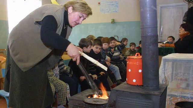 Женщина разжигает печку в детском саду 