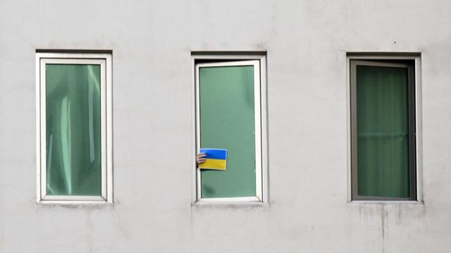 Михаил Саакашвили показывает украинский флаг с окна клиники 