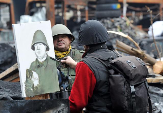 Протестующий рисует портрет у баррикады