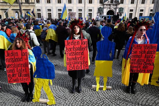 Люди с плакатами и украинскими флагами