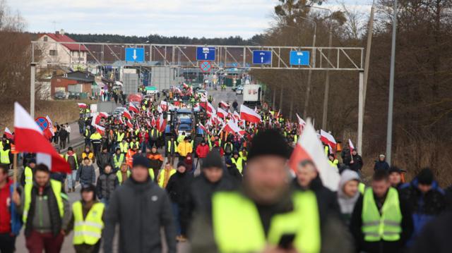 Люди с польскими флагами идут по дороге