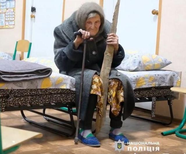 Старая женщина на кровати с двумя палками в руках