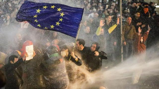 Протестующие с флагом Европы, которых разгоняют с применением водомета на акции в Тбилиси в марте 2023 года