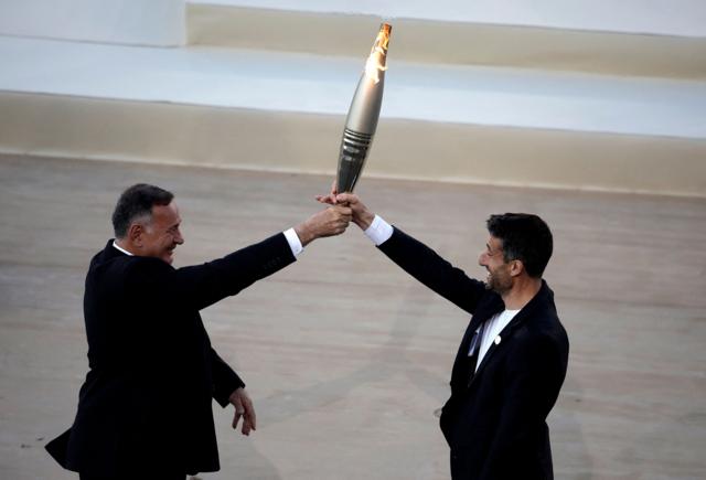 Глава Олимпийского комитета Греции Спирос Капралос передает Олимпийский огонь руководителю оргкомитета Олимпиады в Париже Тони Эстанге