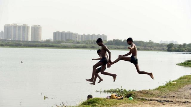 Подростки купаются в реке, чтобы охладиться
